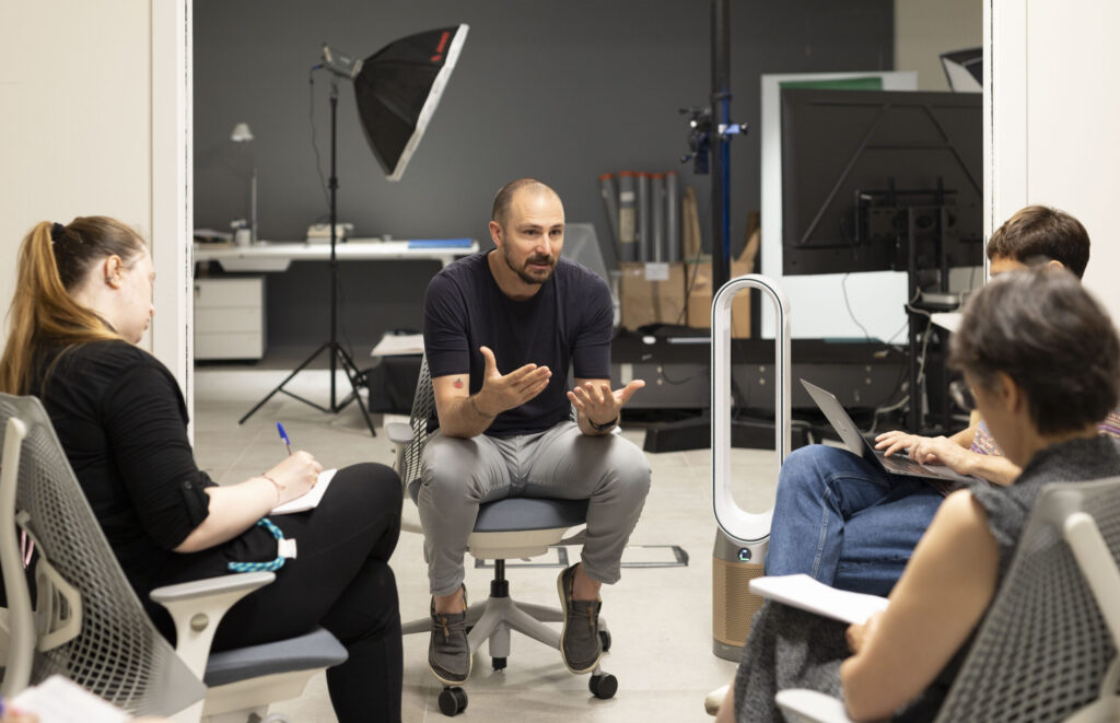 Joan Porcel, fotografo della Fondazione Giorgio Cini, durante una sessione formativa in Heritage Lab con un gruppo di partecipanti, in un ambiente attrezzato per la digitalizzazione.